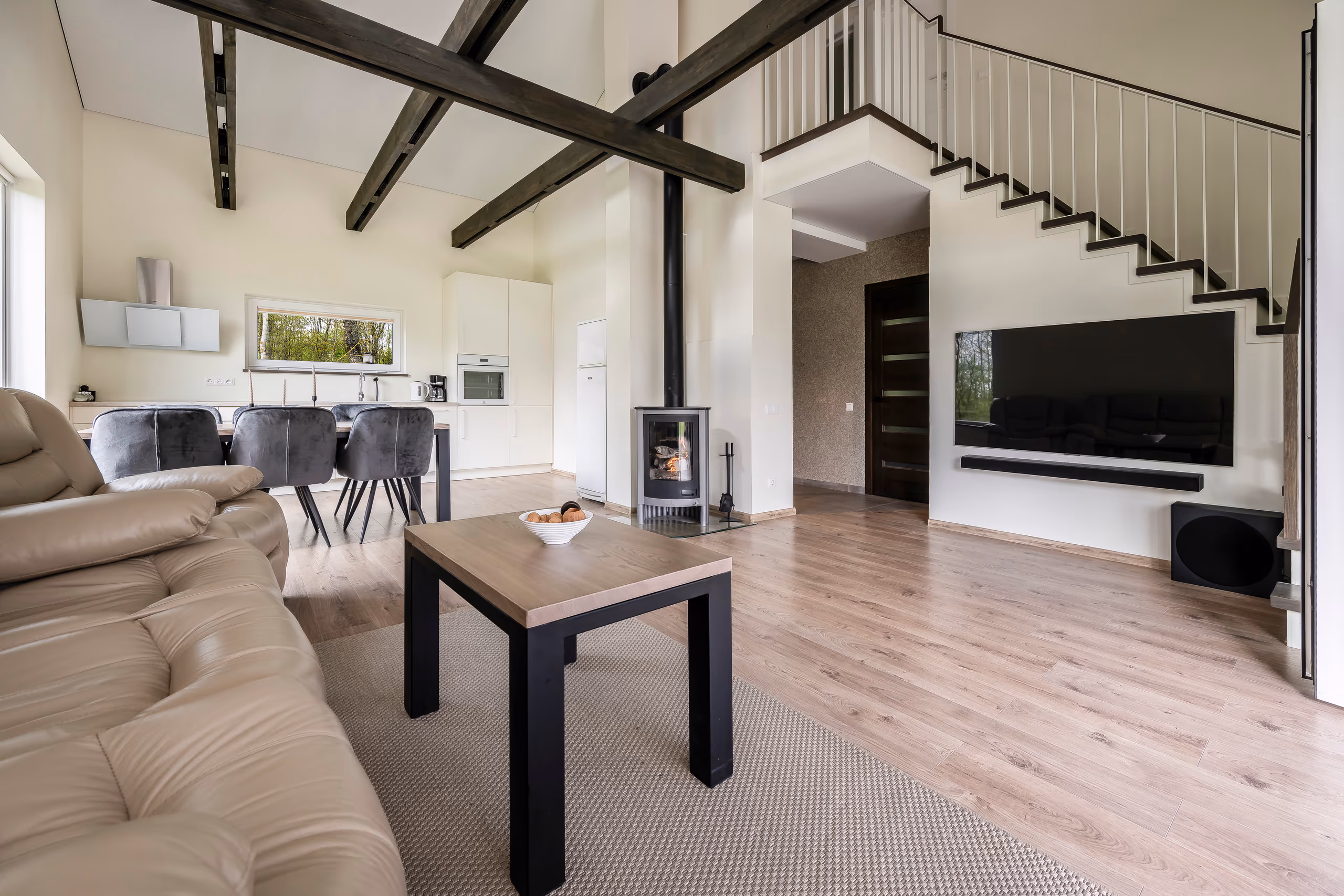 Vila Valentino open-plan room: living with leather sofa, dining, white kitchen, wood stove and stairs